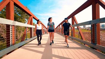 Three people are walking on a bridge.at Linc, Des Moines, IA 50309  